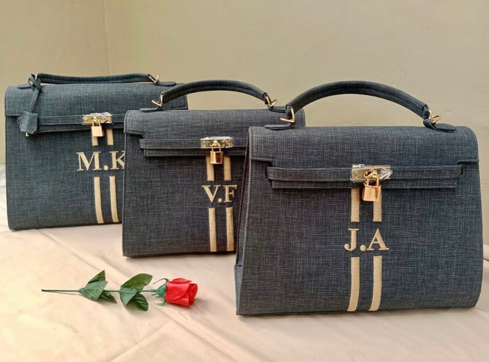 Three custom O'Kelly tote bags in dark gray with gold locks and personalized initials by Travellers Hat Boutique
