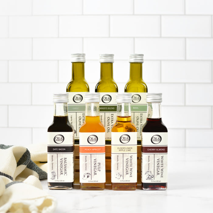 Collection of various vinegar bottles on a kitchen counter with a white tiled backsplash.