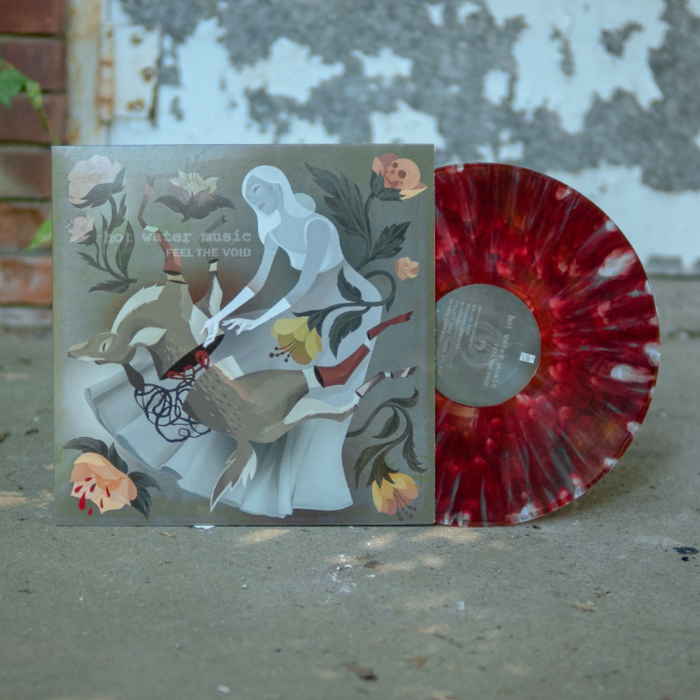 Vinyl jacket with artwork of a woman wearing a long grey dress in the center. The woman is reaching down onto her legs where there is a deer that has been split in half. In each corner is drawings of light pink flowers, one of them having a skull blooming out of it. In the top left corner there is text that lightly says HOT WATER MUSIC and below it there is text that says FEEL THE VOID. There is a ruby with pearl splattered vinyl peeking out of the side. Both are sitting on top of concrete.