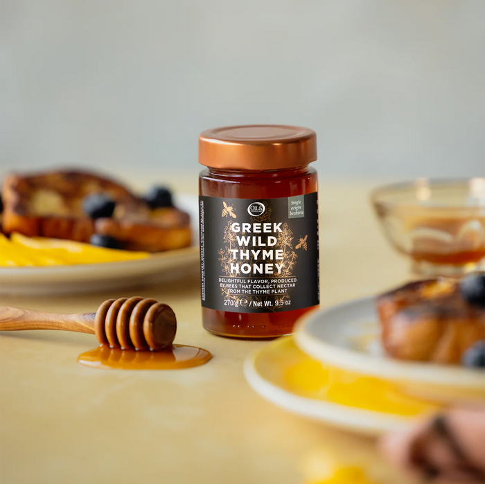 Greek wild thyme honey jar on a table with a honey spoon and french toast beside it