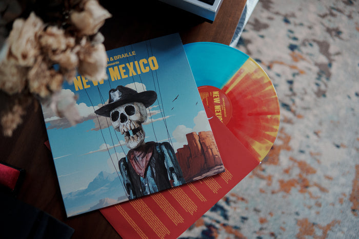 A vibrant blue and yellow vinyl record by Anchor & Braille sits beside its cover, which shows a skeleton puppet in a cowboy hat with New Mexico text—an ideal pick for any New Mexico vinyl collector's 2025 wish list.