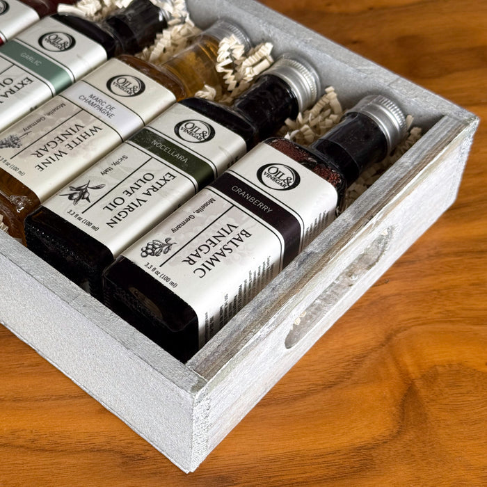 Set of olive oil and vinegar bottles in a wooden box on a wooden surface