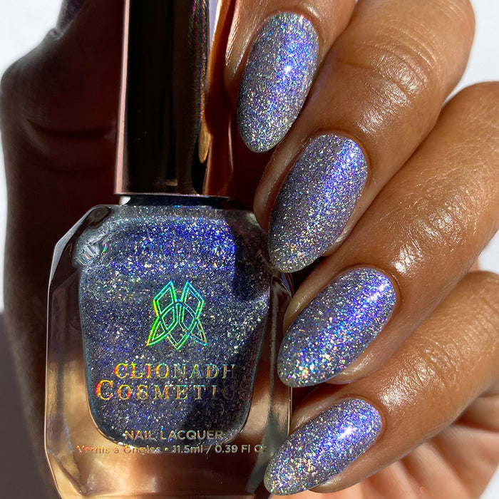 Close-up of nails painted with Spilled Salt Nail Lacquer on medium skin tone. Hand is holding polish bottle.