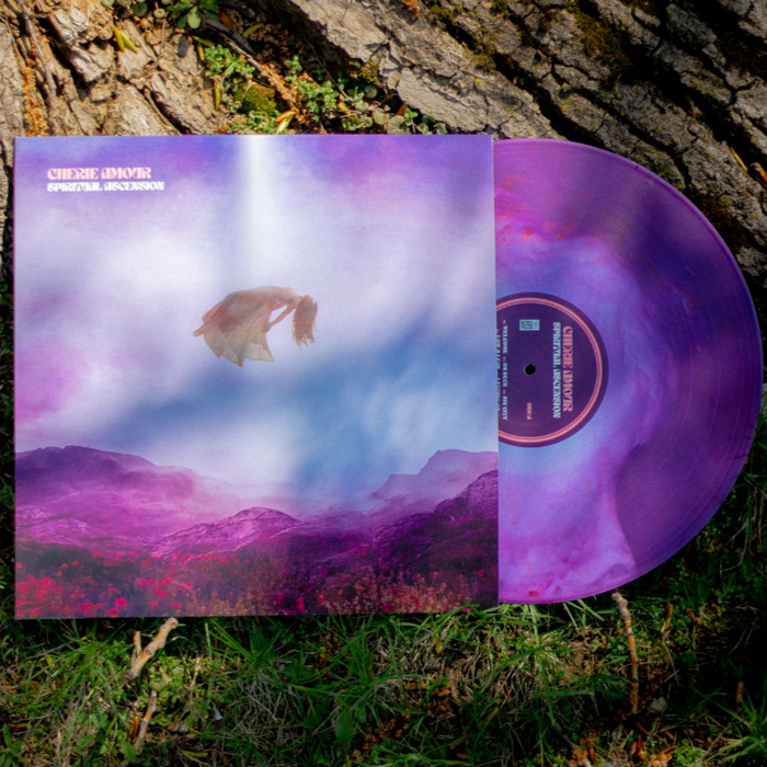 A limited edition Cherie Amour vinyl in a purple/white/pink mix slides out, showing surreal Spiritual Ascension artwork with a floating figure above misty purple grass beside a tree.