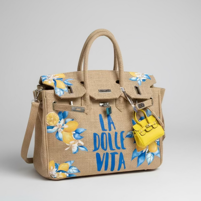 Beige handbag with floral designs and 'La Dolce Vita' text on a light gray background