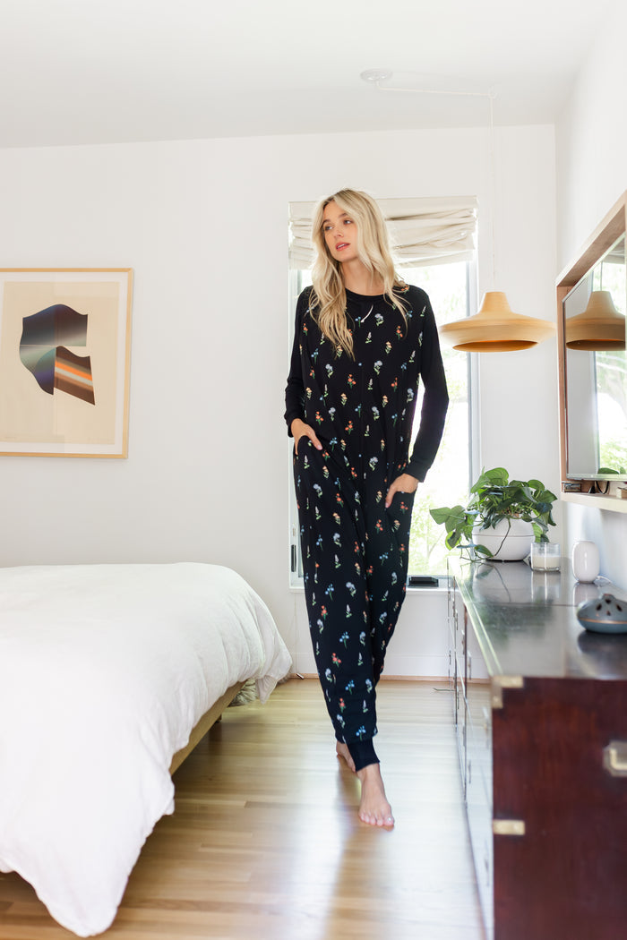 Model wearing Adult Sleeveless Sleep Bag Walker in Midnight Wildflower print in bedroom