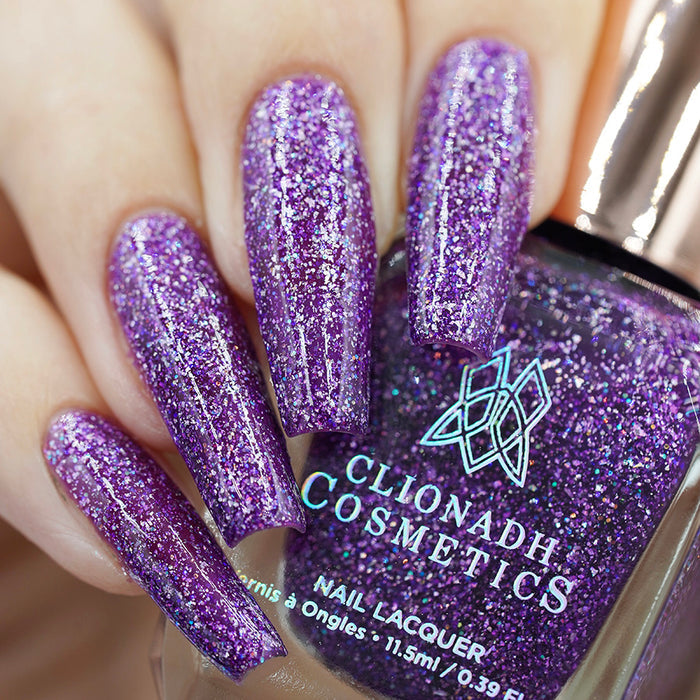 Close-up of nails painted with Armadillo's Night Out Nail Lacquer on fair skin tone. Hand is holding polish bottle.