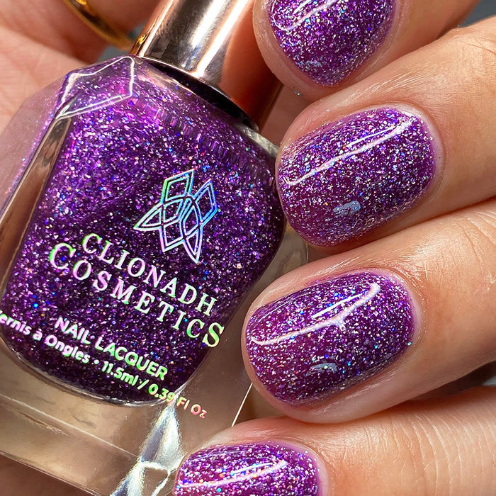 Close-up of nails painted with Armadillo's Night Out Nail Lacquer on fair skin tone. Hand is holding polish bottle.