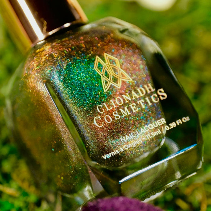 Angled, close-up of Baeocystin Nail Lacquer bottle, on a blurred grass background.