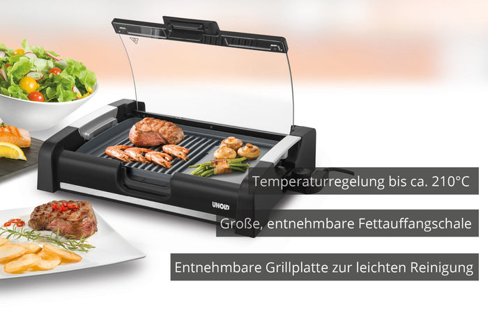 Der Unold Barbecue-Grill Edel ist ein elektrischer Tischgrill mit transparentem Deckel, Grillfleisch und Gemüse, einer Salatschüssel in der Nähe, Temperaturregelung bis 210 °C und abnehmbarem Grillrost und Fettauffangschale zur einfachen Reinigung.