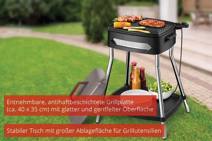 Der Unold Barbecue Power Grill, hier in Schwarz mit Grillgut, steht auf einem stabilen Gartentisch. Auf der unteren Ablage liegen Gewürze. Der Deckel liegt auf dem Rasen daneben, und rote Kästen zeigen deutsche Texte, die seine Funktionen hervorheben.