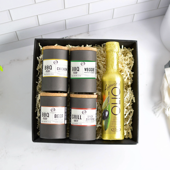 Set of BBQ seasonings and a bottle of olive oil in a gift box on a white countertop.
