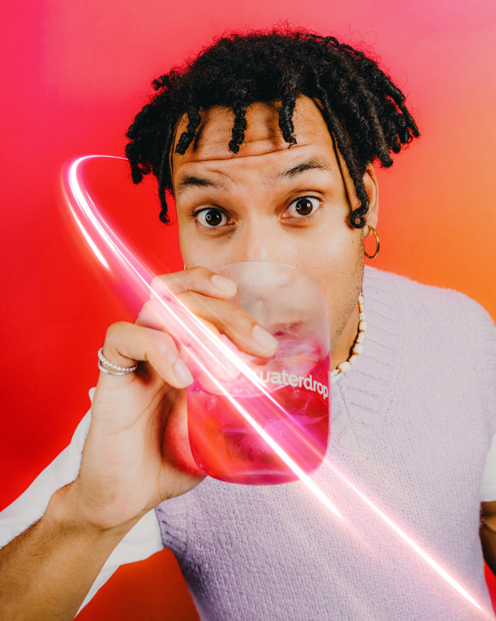 Young person sipping BERRY BOOST from a translucent waterdrop cup.