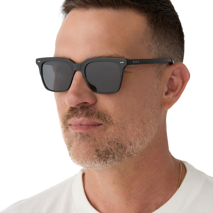 on model - male wearing Billie sunglasses with black frame and grey polarized lens-angled view