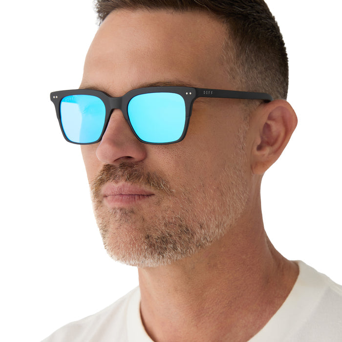 on model - male wearing Billie sunglasses with matte black frame and blue mirror lens angled view