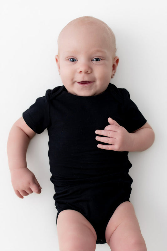 Baby wearing a black onesie on a white background