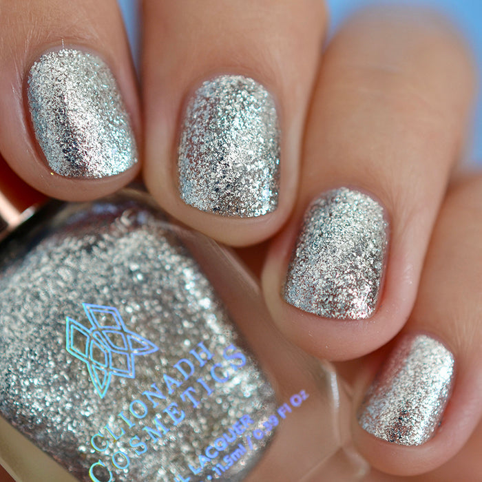 Close-up of nails painted with Broken Mirror Nail Lacquer on fair skin tone. Hand is holding polish bottle.