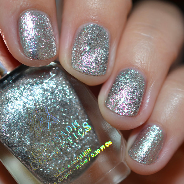 Close-up of nails painted with Broken Mirror Nail Lacquer on fair skin tone. Hand is holding polish bottle.