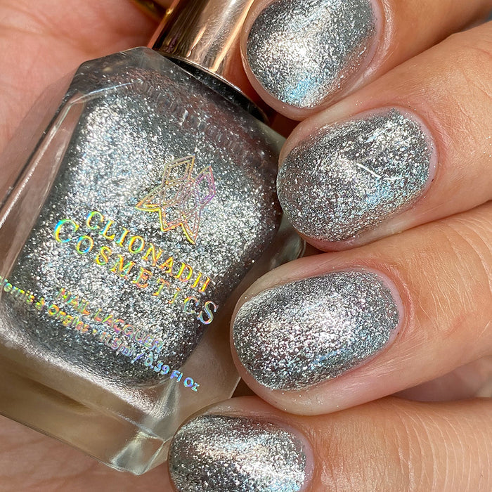 Close-up of nails painted with Broken Mirror Nail Lacquer on fair skin tone. Hand is holding polish bottle.