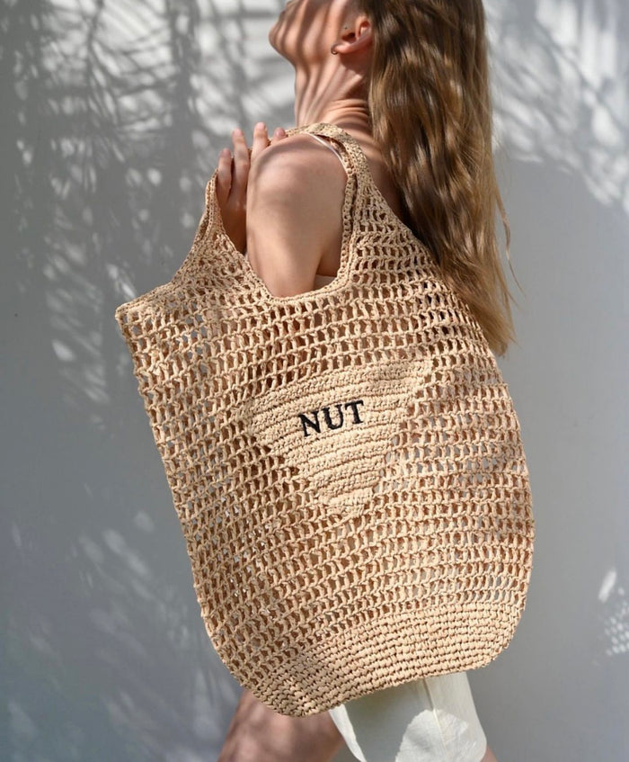 Handmade raffia bucket bag tote by Travellers Hat Boutique worn by woman in natural light