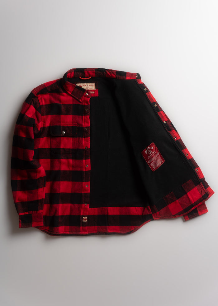 Red and black plaid flannel shirt with black lining, open to reveal interior label and snap buttons on a light background.