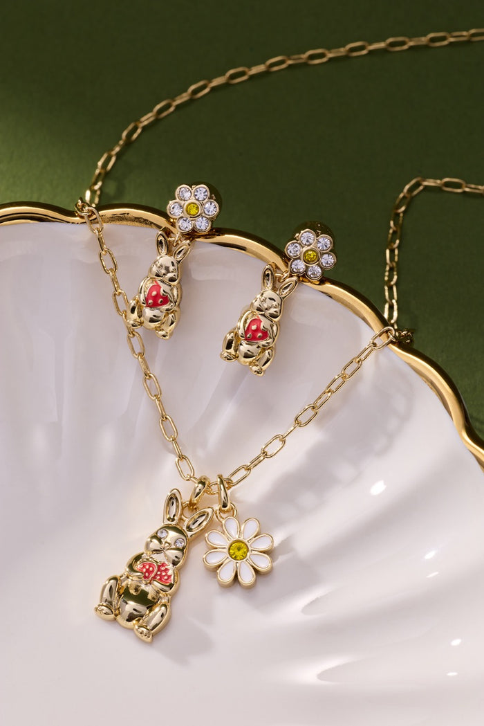 Gold jewelry set with floral and animal designs on a white dish.