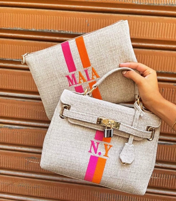 Custom O'Kelly tote bag in beige with orange and pink stripes and gold hardware held by hand