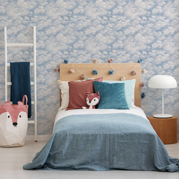 Tempaper's Clouds Peel And Stick Wallpaper in light blue shown in a kids bedroom behind a bed.