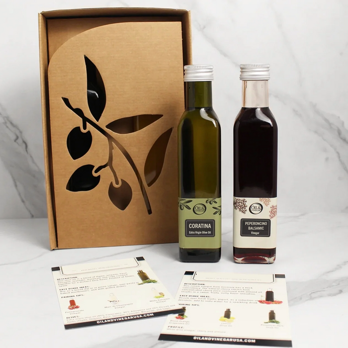 Two bottles of one olive oil and one balsamic vinegar with a decorative box on a white background