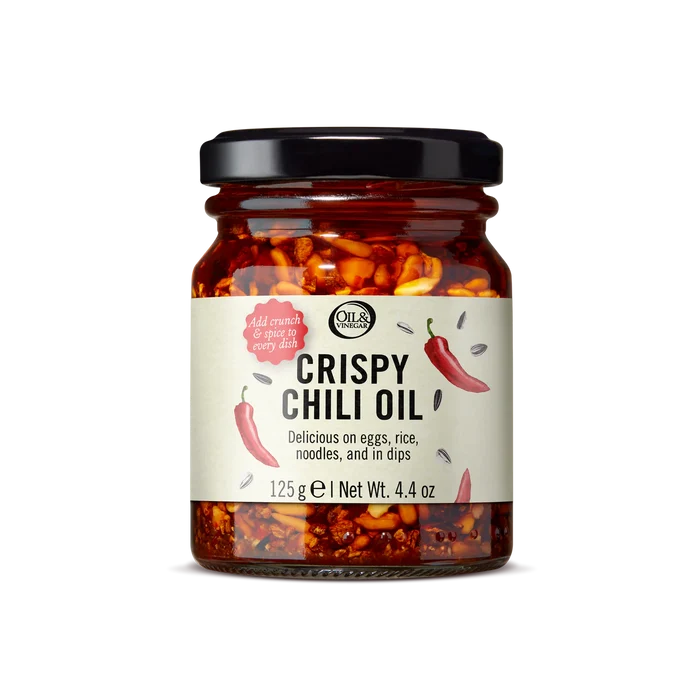 A jar of Crispy Chili Oil with a label showing the product name and an illustration of chili peppers. The jar is sealed and presented against a white background.