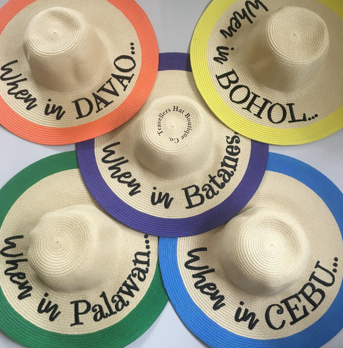 Custom hand-painted floppy hats from Travellers Hat Boutique featuring colorful rims and destination names