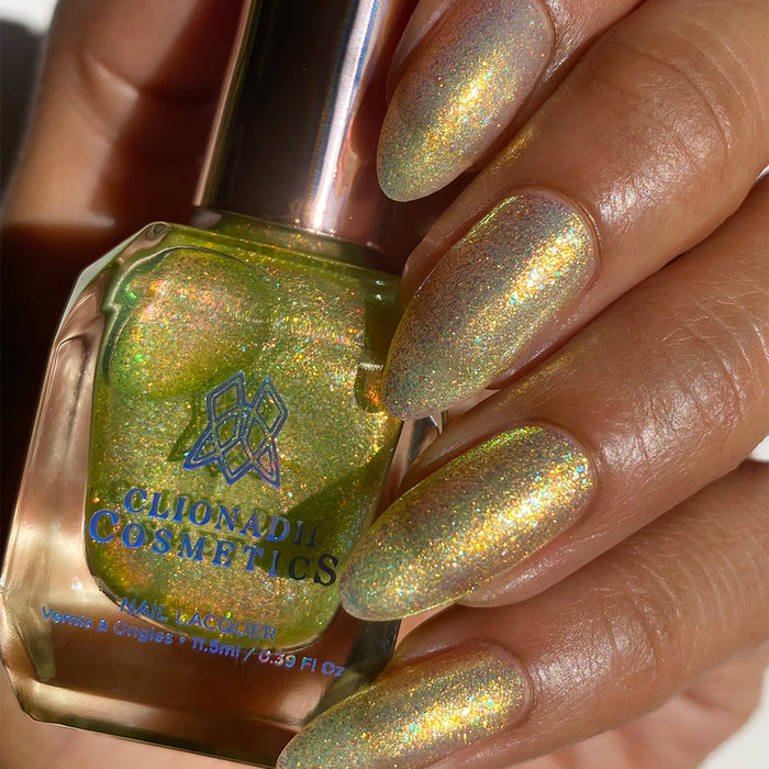 Close-up of nails painted with Dais Nail Lacquer on medium skin tone. Hand is holding polish bottle.