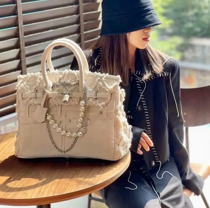 Denim blue jeans handbag tote bag with pearl and chain details by Travellers Hat Boutique on wooden table