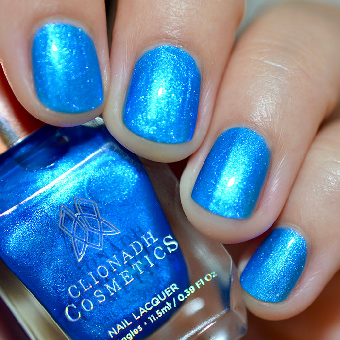 Close-up of nails painted with Don't Open Inside! Nail Lacquer on fair skin tone. Hand is holding polish bottle.
