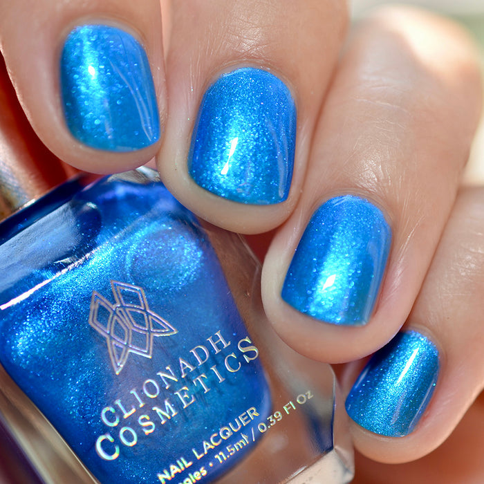 Close-up of nails painted with Don't Open Inside! Nail Lacquer on fair skin tone. Hand is holding polish bottle.