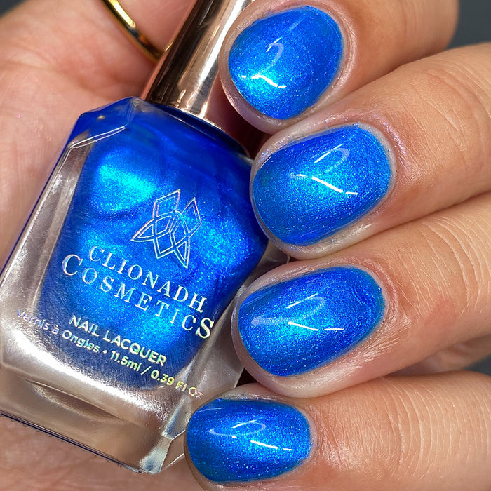 Close-up of nails painted with Don't Open Inside! Nail Lacquer on fair skin tone. Hand is holding polish bottle.