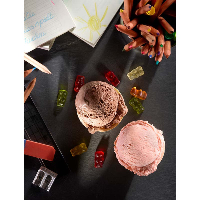Das Eisbuch – 101 Eisrezepte von Unold wird mit zwei Kugeln Eis, Gummibärchen, Buntstiften, einem Spitzer, einem Notizblock und einer Sonnenzeichnung eines Kindes auf dunklem Untergrund gezeigt.