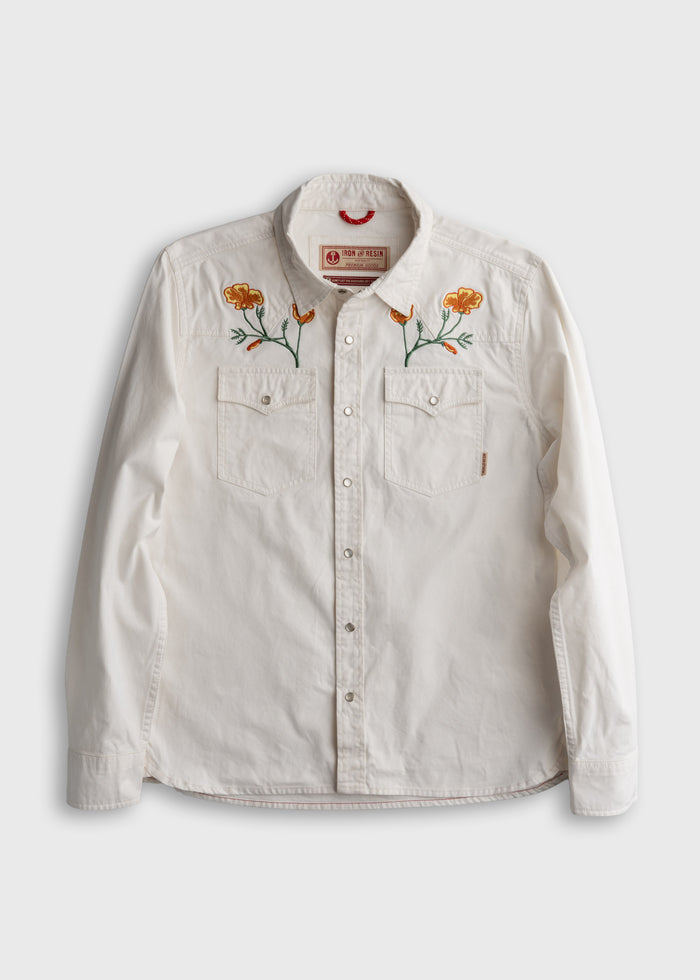 White button-up shirt with orange flower embroidery on the chest, featuring two front pockets.