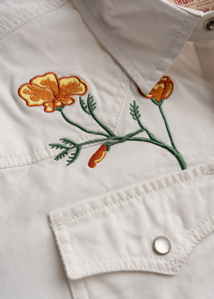 Close up of embroidered poppies, double needle stitching on shoulders and seams, highlighting reinforced durability and class