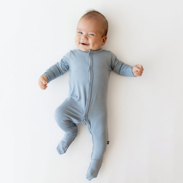 Smiling baby wearing Kyte Baby Footie in Slate
