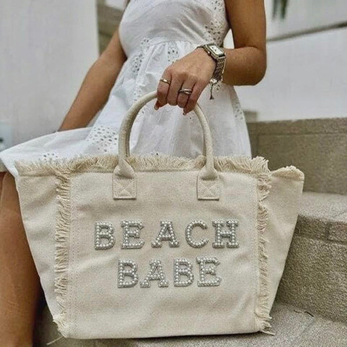 Personalized canvas tote with fringe and beaded Beach Babe text held by woman in white dress