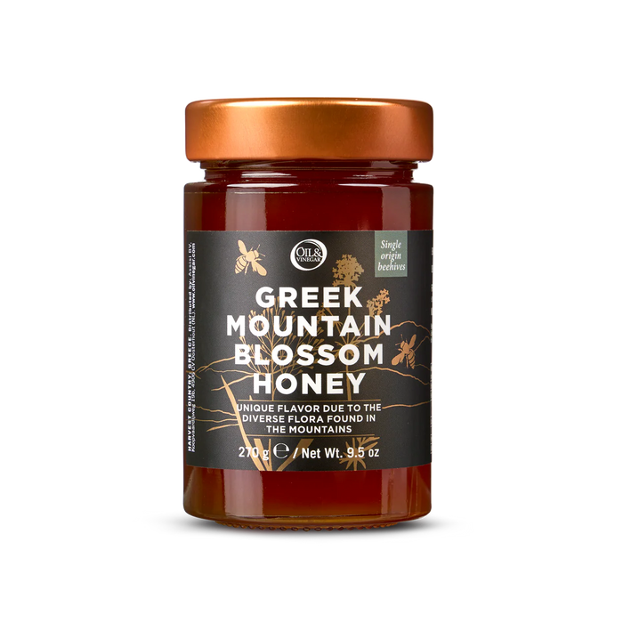 A jar of Greek mountain blossom honey with a label indicating its origin and weight.