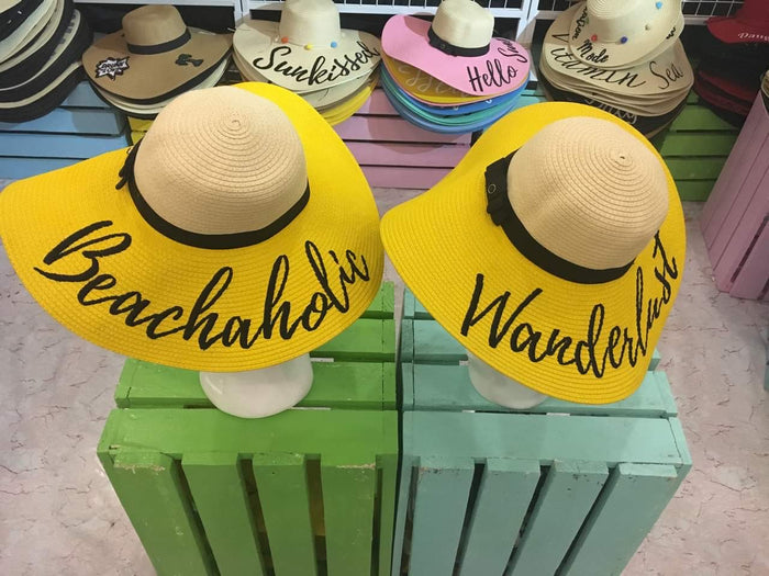 Yellow hand-painted straw hat with wide brim and Wanderlust and Beachaholic text designs
