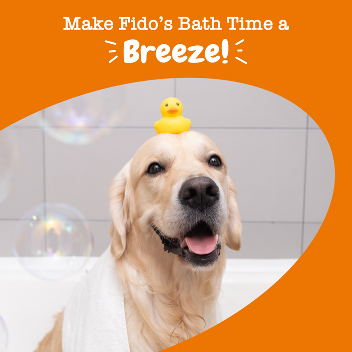 Light-colored dog with yellow rubber duck on head in bathroom with bubbles and white tile background.