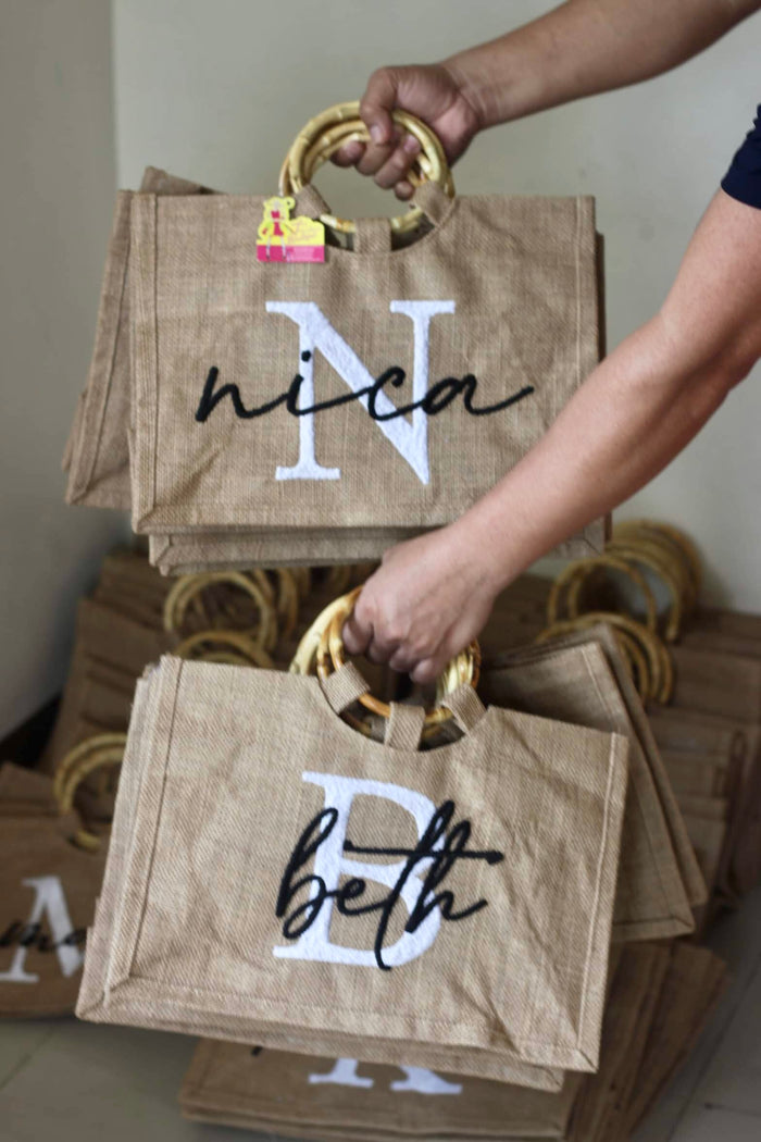 Personalized jute totes with bamboo handles from Travellers Hat Boutique featuring names and initials