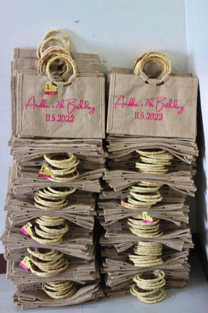 Stack of personalized jute tote bags with bamboo handles for a 7th birthday party