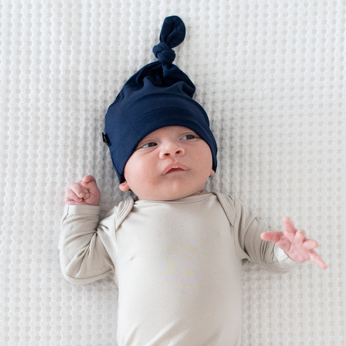 Close up of newborn wearing a Kyte Baby Knotted Cap in Navy