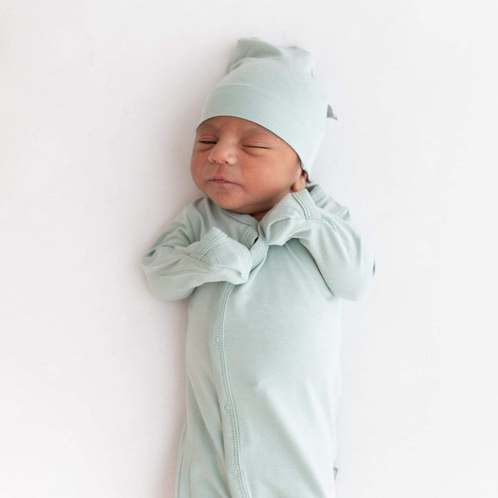 Infant sleeping in Kyte Baby bamboo Knotted Cap in Sage with matching footie