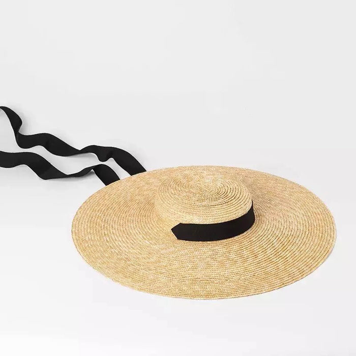 Large wheat straw hat with wide brim and black ribbon tie by Travellers Hat Boutique