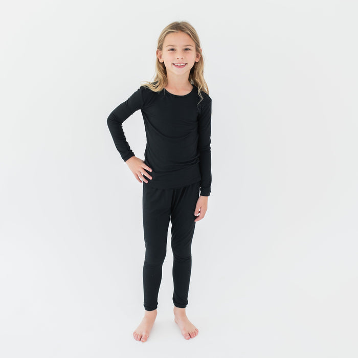 Young girl standing with one hand on her hip wearing the Long Sleeve Pajamas in Midnight in front of a white background